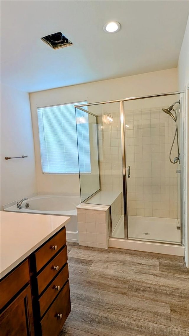 bathroom with independent shower and bath, wood-type flooring, and vanity