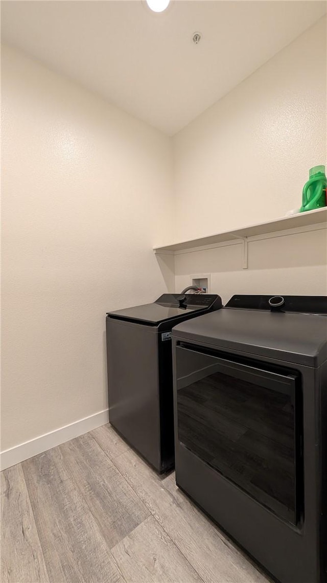 clothes washing area featuring light wood-type flooring and washer and clothes dryer