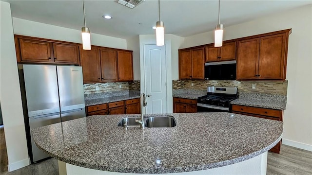 kitchen featuring appliances with stainless steel finishes, sink, an island with sink, and hanging light fixtures