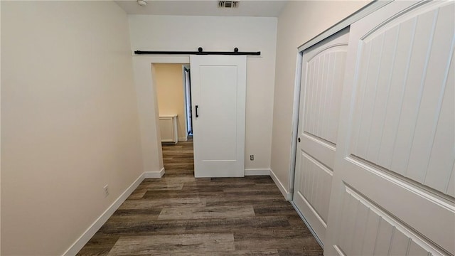 hall with dark wood-type flooring and a barn door