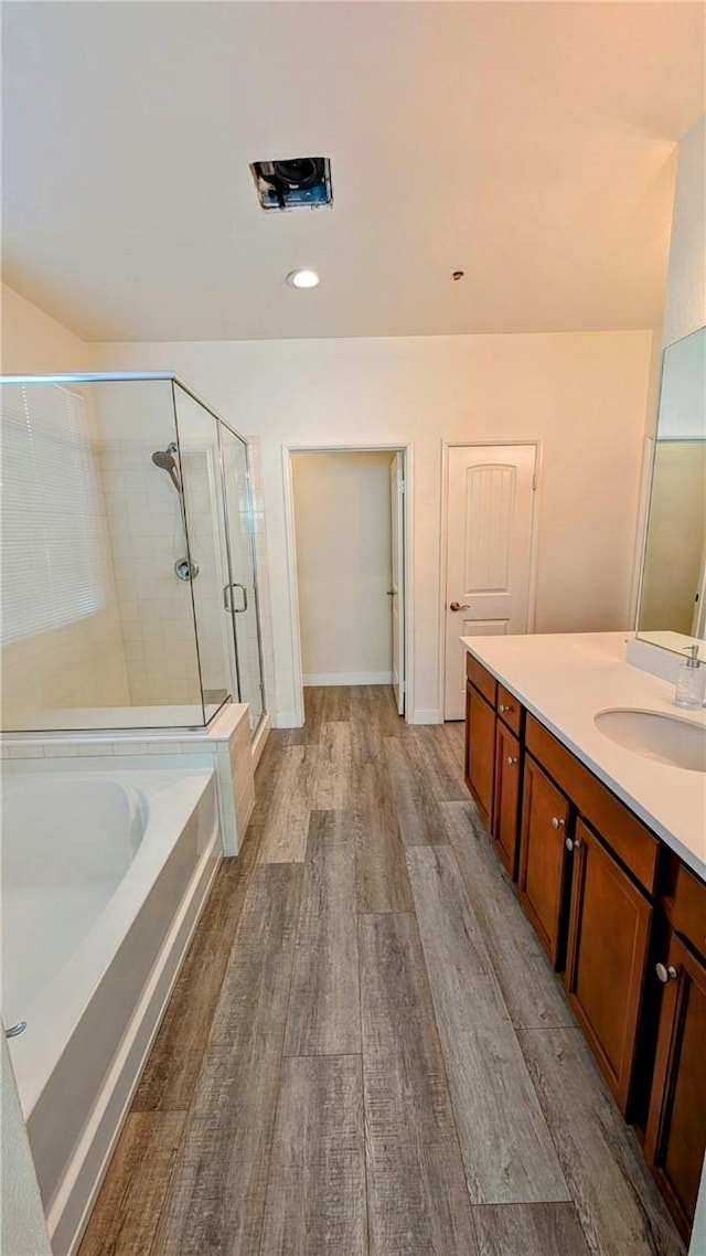 bathroom featuring vanity, hardwood / wood-style floors, and plus walk in shower