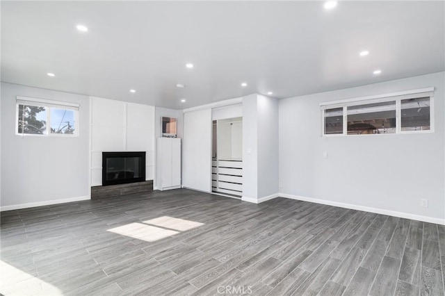 unfurnished living room featuring recessed lighting, baseboards, wood finished floors, and a fireplace