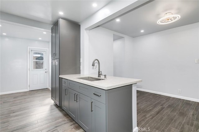 kitchen featuring light countertops, wood finished floors, a sink, and gray cabinetry