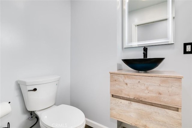 bathroom featuring toilet, vanity, and baseboards