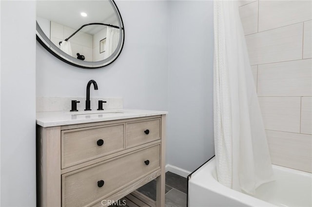 full bath featuring baseboards, vanity, and shower / bathtub combination with curtain