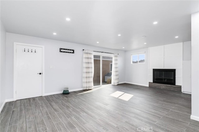 unfurnished living room featuring baseboards, a large fireplace, and wood finished floors