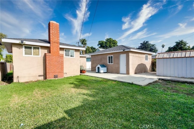 back of house with stucco siding, an outdoor structure, and a patio