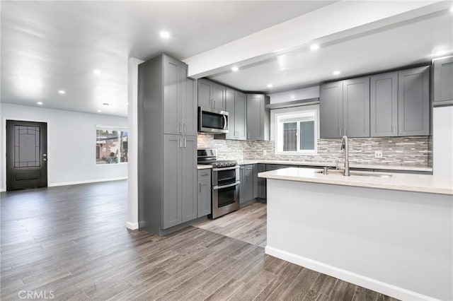 kitchen with light countertops, a sink, appliances with stainless steel finishes, and gray cabinets