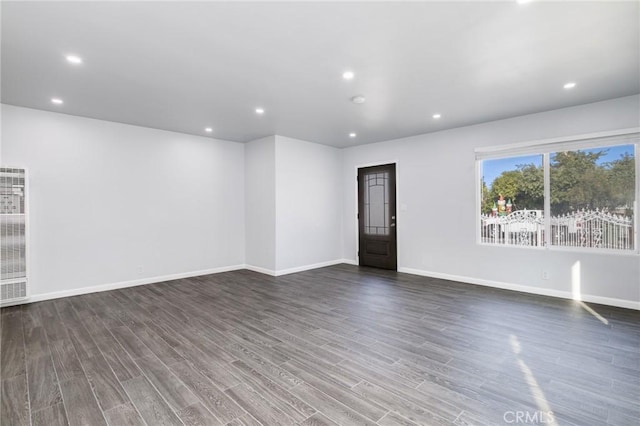 spare room featuring baseboards, wood finished floors, and recessed lighting