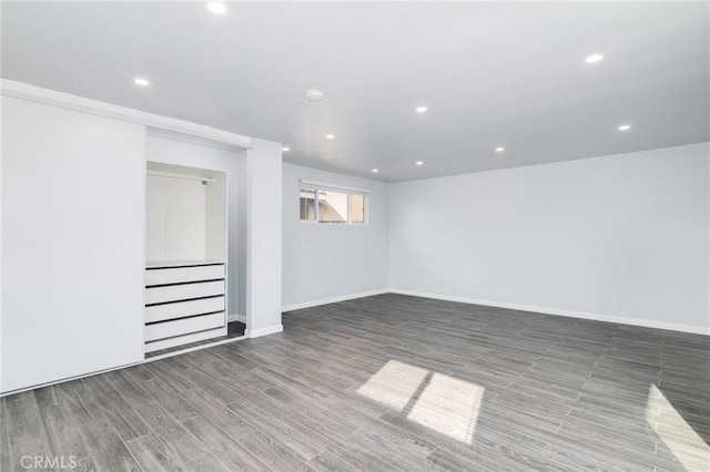 below grade area featuring baseboards, wood finished floors, recessed lighting, and stairway