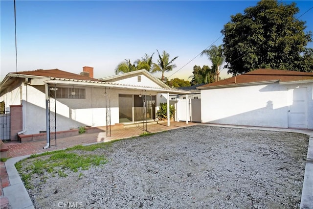 back of property featuring a chimney, a patio area, and a gate