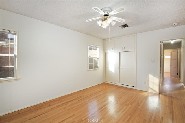 unfurnished bedroom with light wood-style floors, a closet, visible vents, and a textured ceiling