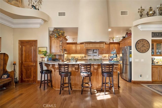 41700 Jojoba Hills Cir, Aguanga, CA 92536 - kitchen with a kitchen bar, kitchen peninsula, a towering ceiling, stainless steel appliances, and hardwood / wood-style floors