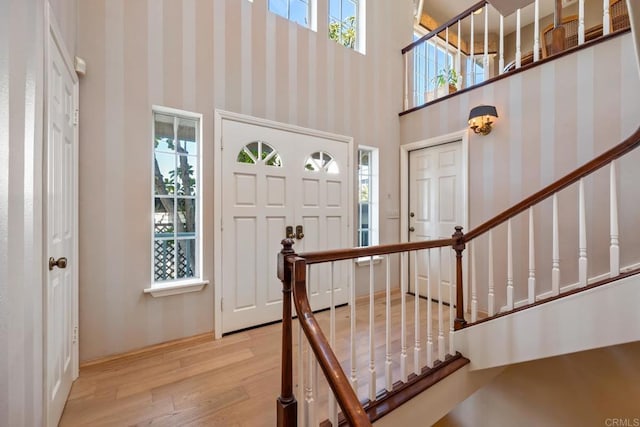 entryway featuring a towering ceiling and light wood-type flooring