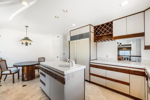 kitchen with white cabinetry, sink, hanging light fixtures, a center island, and tile counters