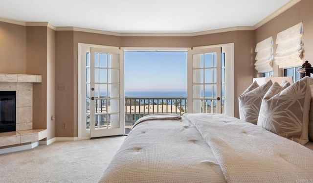 bedroom with a tiled fireplace, light carpet, ornamental molding, and a water view