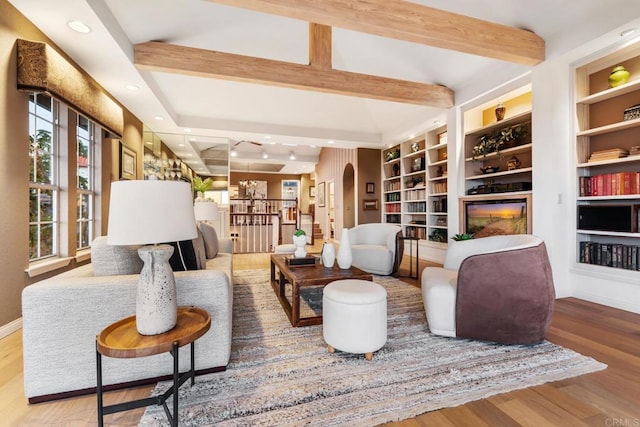 living area with hardwood / wood-style flooring, beam ceiling, and built in shelves