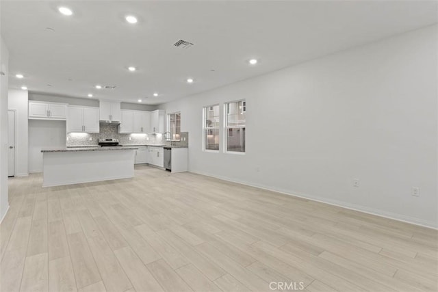 kitchen featuring visible vents, open floor plan, white cabinetry, appliances with stainless steel finishes, and decorative backsplash