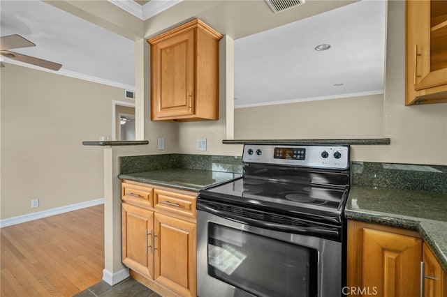 kitchen featuring crown molding, stainless steel range with electric stovetop, dark stone countertops, ceiling fan, and hardwood / wood-style floors