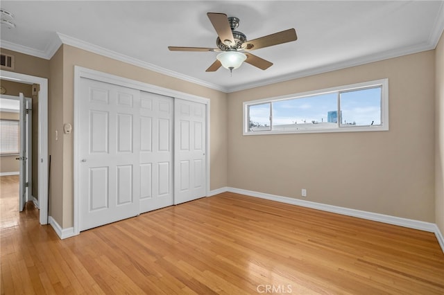 unfurnished bedroom with ornamental molding, a closet, ceiling fan, and light wood-type flooring