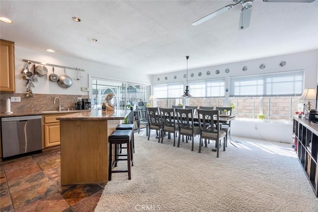 kitchen with sink, a breakfast bar area, dishwasher, pendant lighting, and decorative backsplash