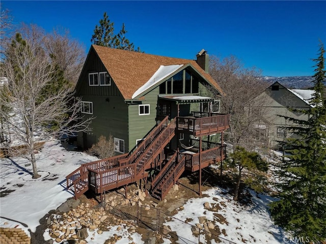 snow covered house featuring a wooden deck