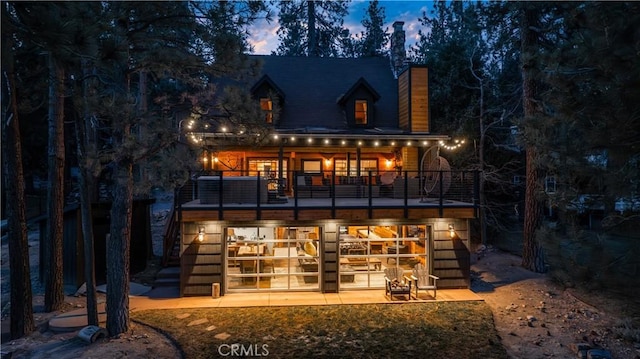 back house at dusk featuring a balcony and a patio area