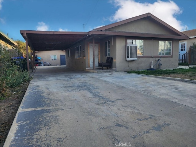 view of front facade featuring concrete driveway, a carport, and stucco siding