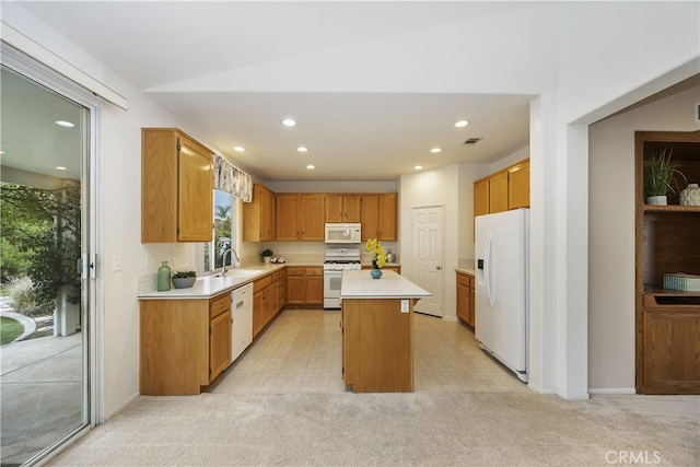 kitchen with white appliances, sink, a center island, and light colored carpet