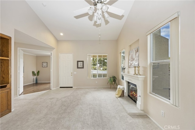 unfurnished living room featuring a tiled fireplace, light carpet, and ceiling fan