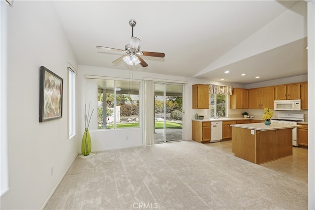 kitchen featuring lofted ceiling, sink, a center island, light colored carpet, and white appliances