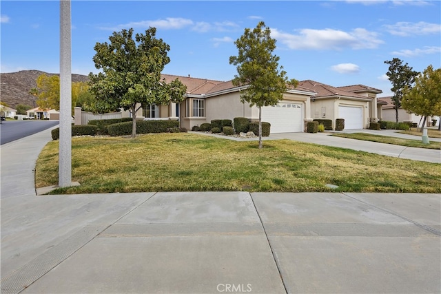 single story home with a garage, a mountain view, and a front lawn