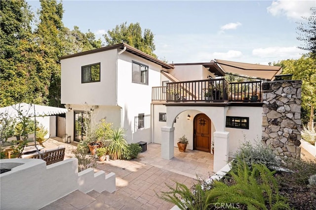 rear view of property with a balcony and a patio area