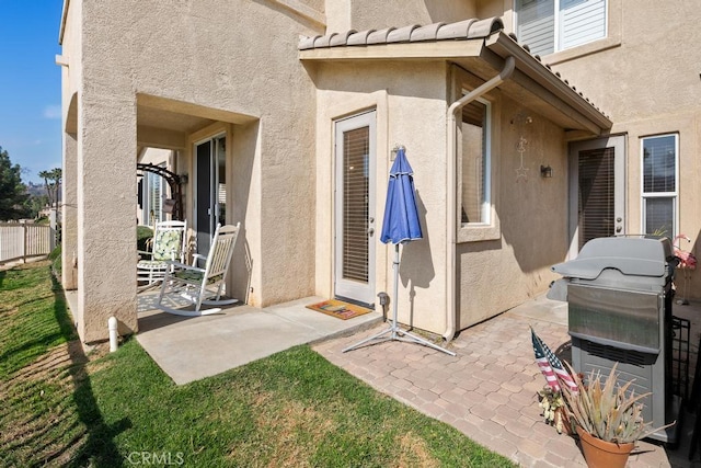 doorway to property featuring a tile roof, a patio, and stucco siding