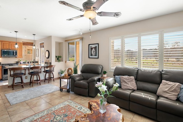 living room with light tile patterned floors, ceiling fan, and baseboards