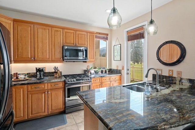 kitchen with dark stone countertops, stainless steel appliances, a peninsula, and a sink