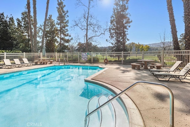 pool with a patio area, fence, and a mountain view