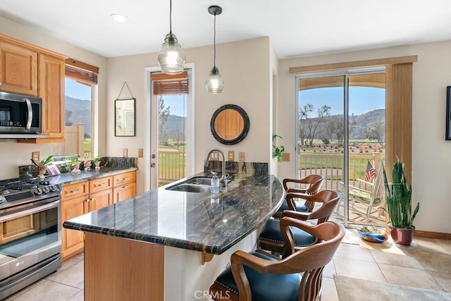 kitchen featuring appliances with stainless steel finishes, a kitchen breakfast bar, decorative light fixtures, a peninsula, and a sink