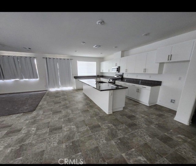 kitchen with white cabinetry, sink, a kitchen island with sink, and appliances with stainless steel finishes