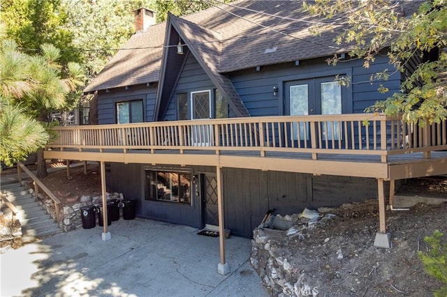 rear view of house featuring a wooden deck and a patio area