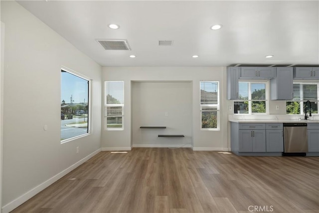 interior space with gray cabinetry, sink, stainless steel dishwasher, and light wood-type flooring