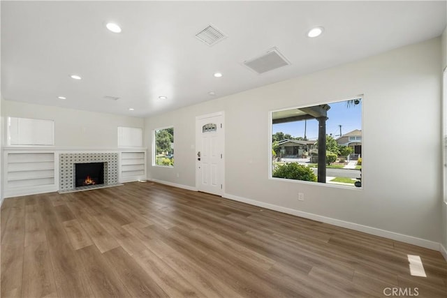 unfurnished living room featuring a tiled fireplace and wood-type flooring