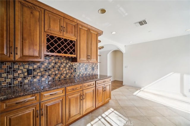 kitchen with backsplash, light tile patterned floors, and dark stone counters