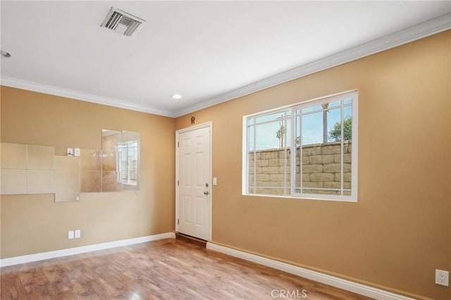 spare room featuring ornamental molding and light hardwood / wood-style flooring