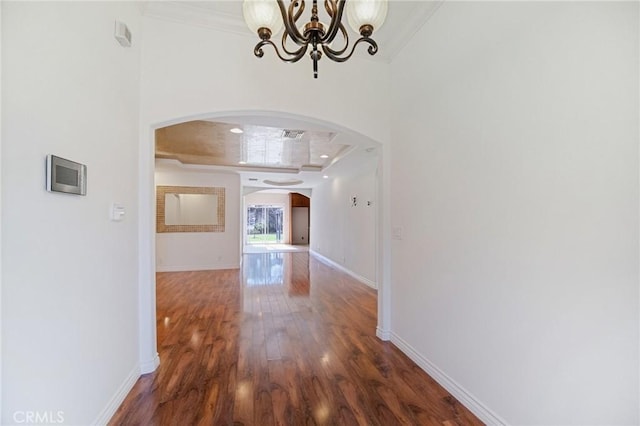 corridor with ornamental molding, dark hardwood / wood-style flooring, and a chandelier