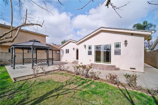 rear view of property featuring a gazebo, a yard, and a patio area