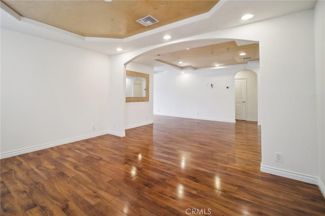 empty room with a raised ceiling and dark hardwood / wood-style floors