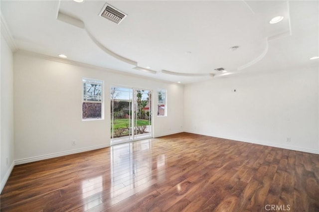 spare room featuring a raised ceiling, ornamental molding, and dark hardwood / wood-style floors