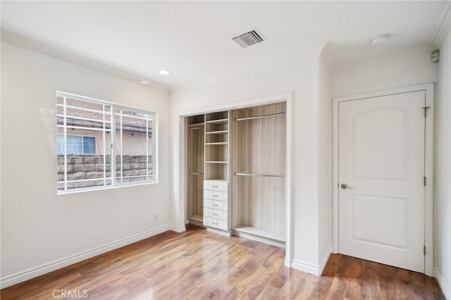 unfurnished bedroom featuring crown molding, hardwood / wood-style floors, and a closet