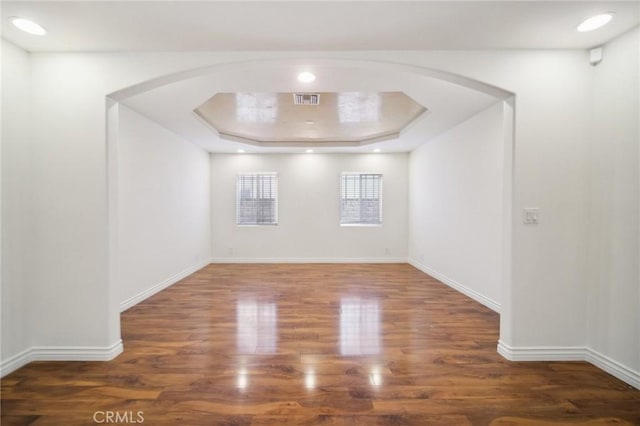 empty room featuring dark hardwood / wood-style floors and a raised ceiling